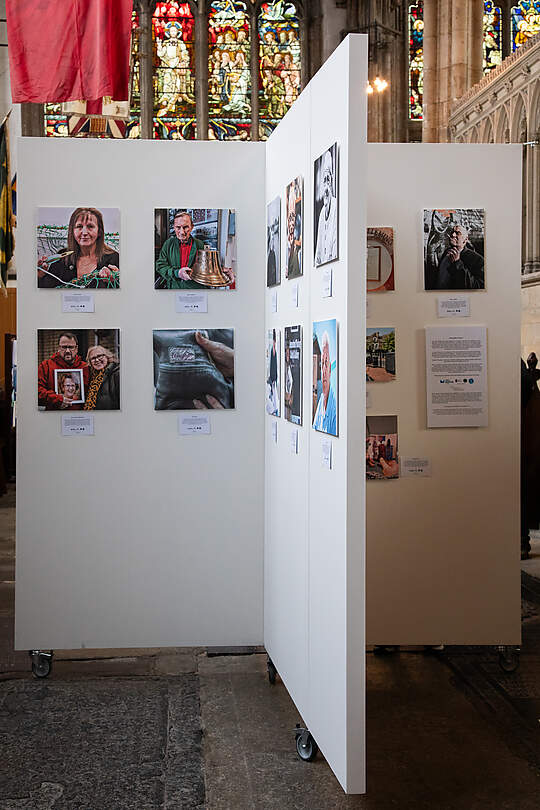 Photos on white stands in exhibition space in a church setting