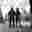Theo McInnes- Kennington Oasis Image shows a black and white full body portrait of two people stood beside each other in a park. They are wearing fencing uniform, including masks covering their faces, and holding épées.